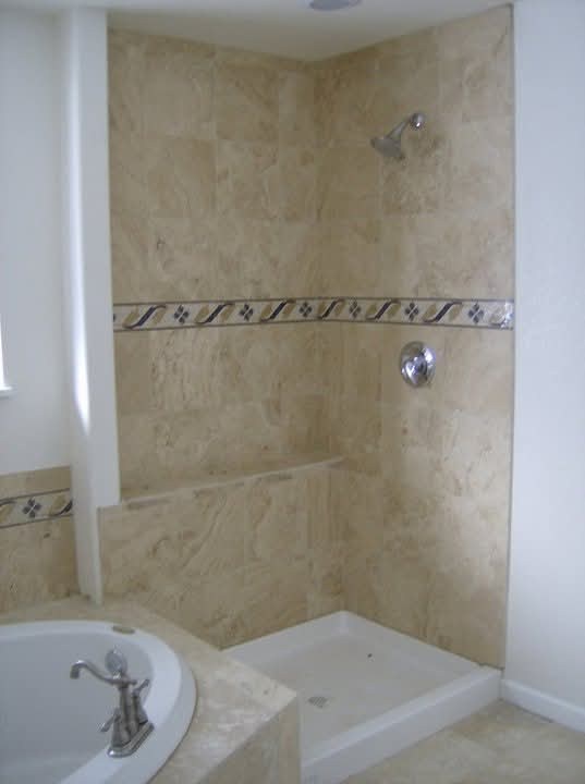 Tiled shower walls with a decorative accent border.