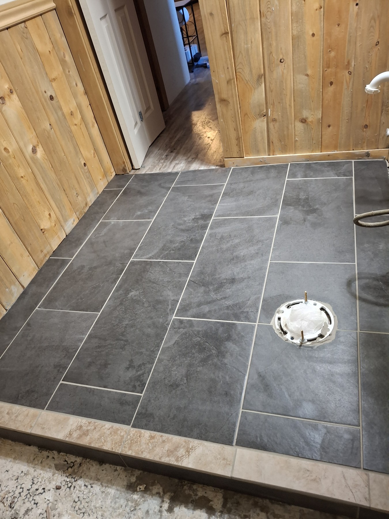 Dark slate-look floor tiles in a wood-paneled entry.