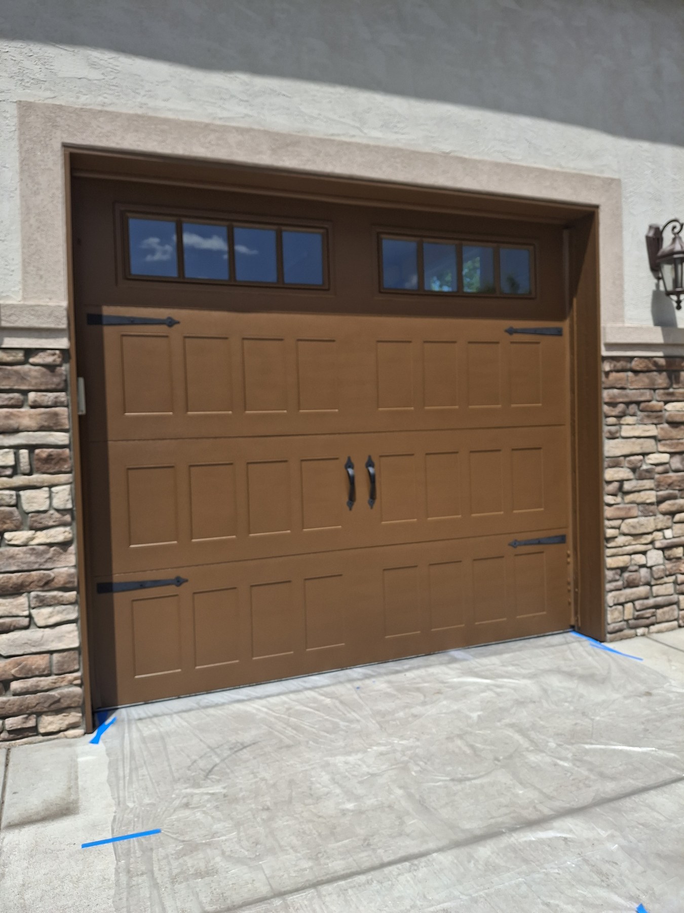 Brown garage door with decorative hardware and upper windows.