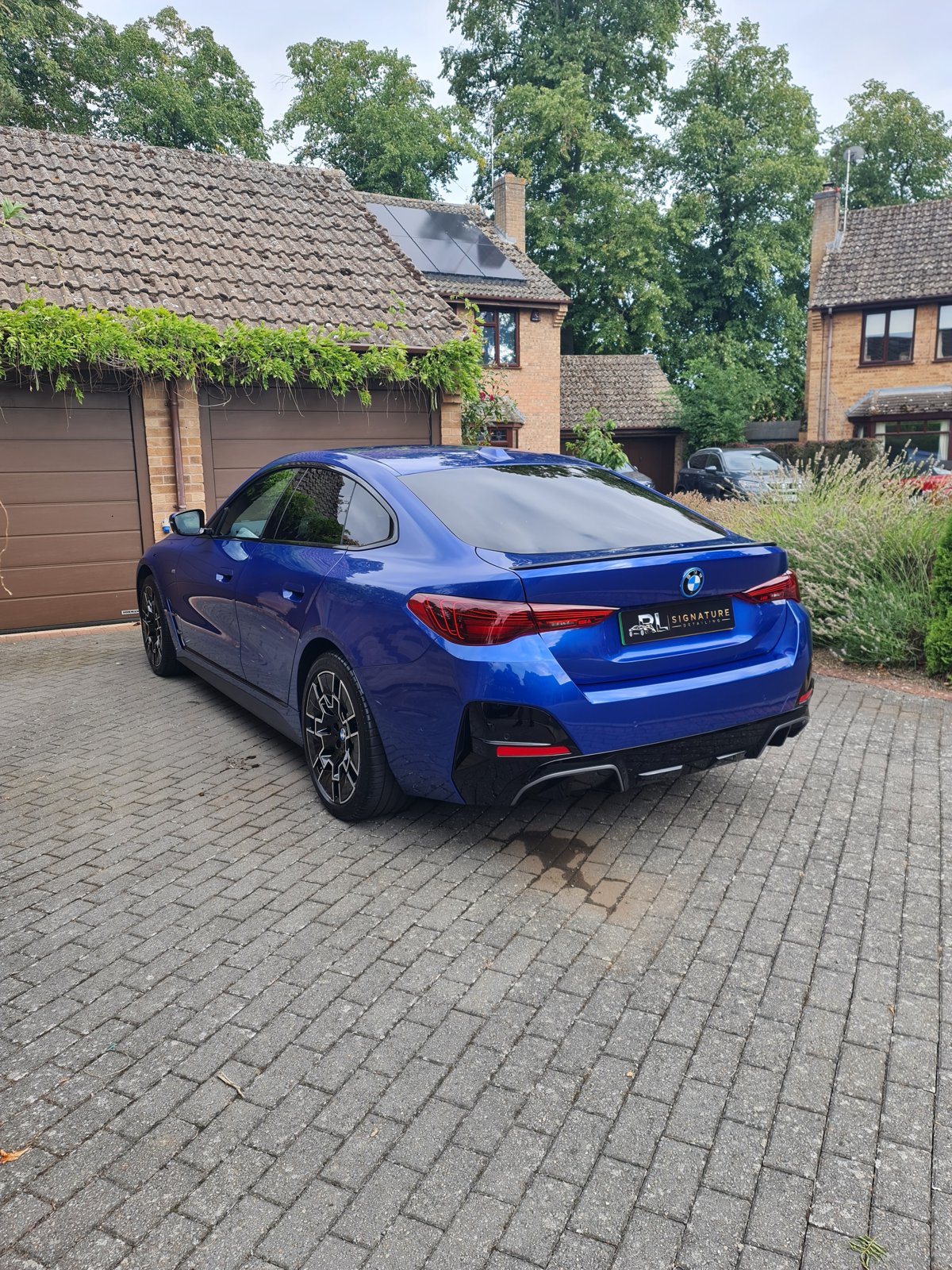Finished blue BMW viewed from the rear on a driveway
