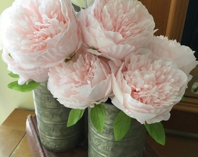 Soft pink peonies arranged in vintage tins