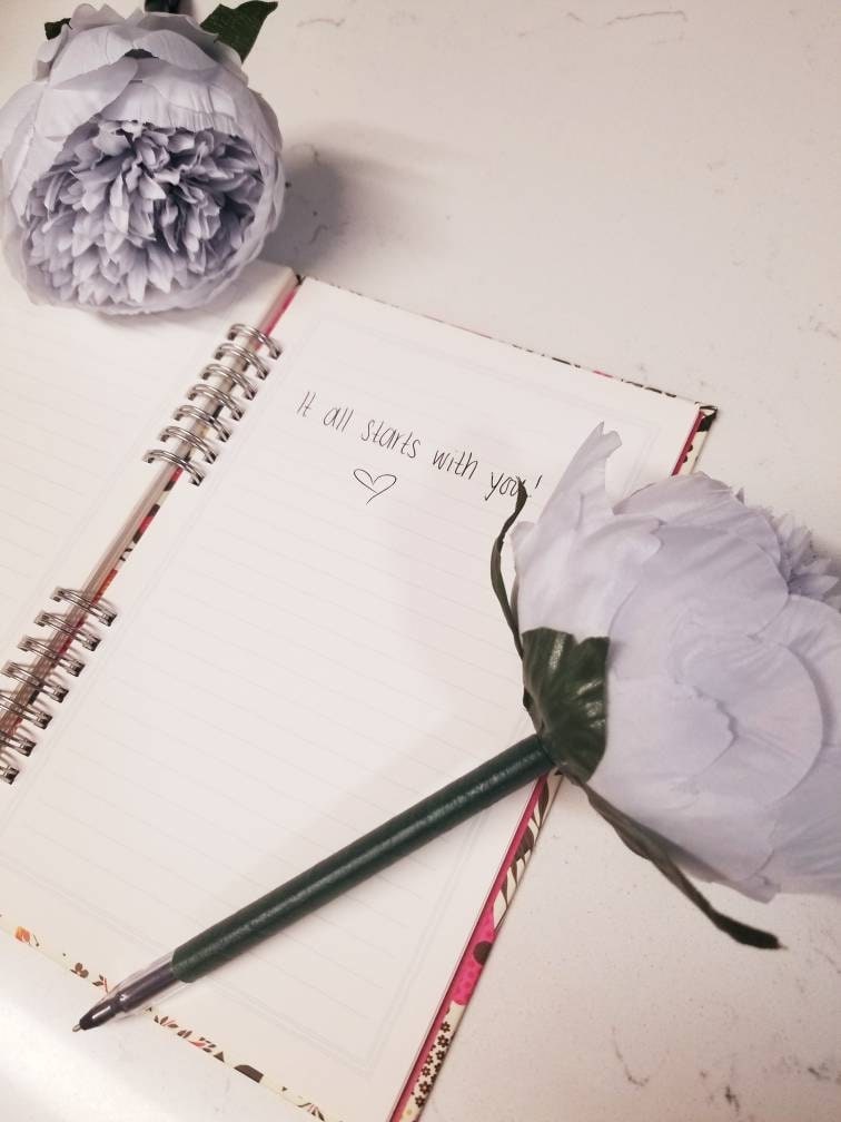 White flower pen beside an open journal