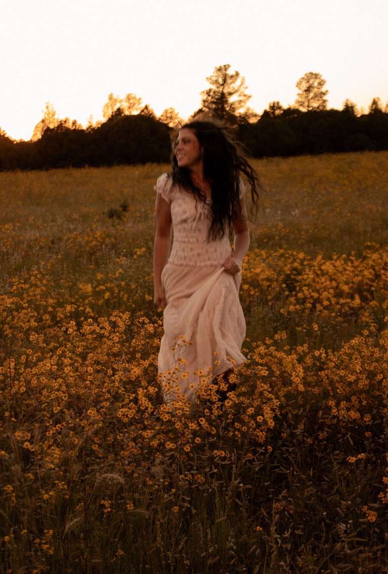 Jessica, the maker behind Lovely Bunches Co, standing in a field of wildflowers at sunset