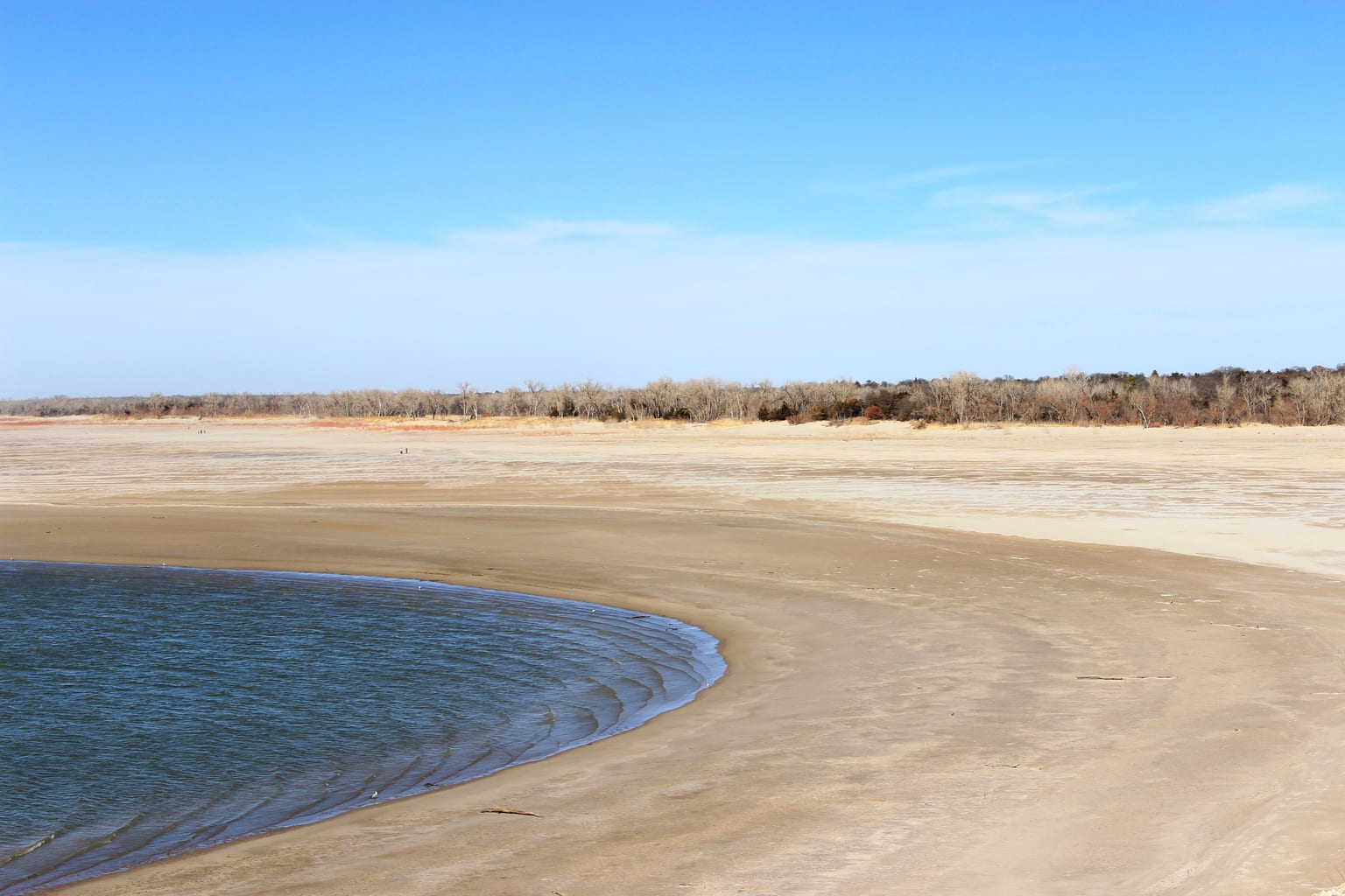 Lowered lake water exposing a broad shoreline during a winter drawdown
