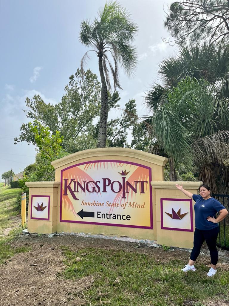 Loyola Pro team member beside the Kings Point entrance sign