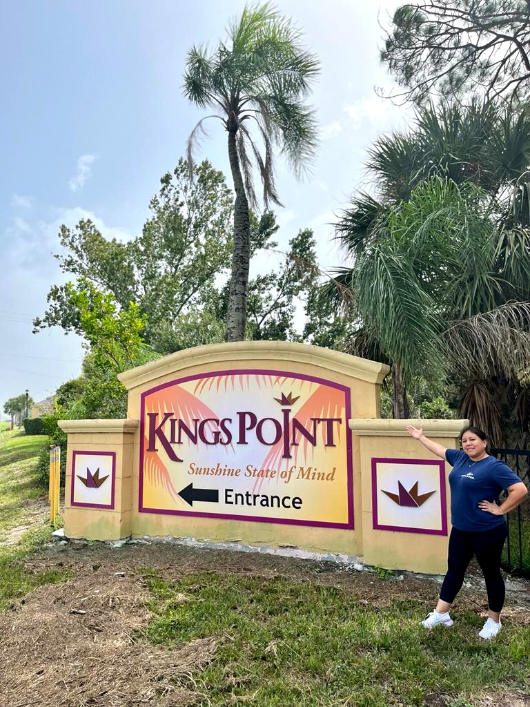 Loyola Pro team member beside the Kings Point entrance sign