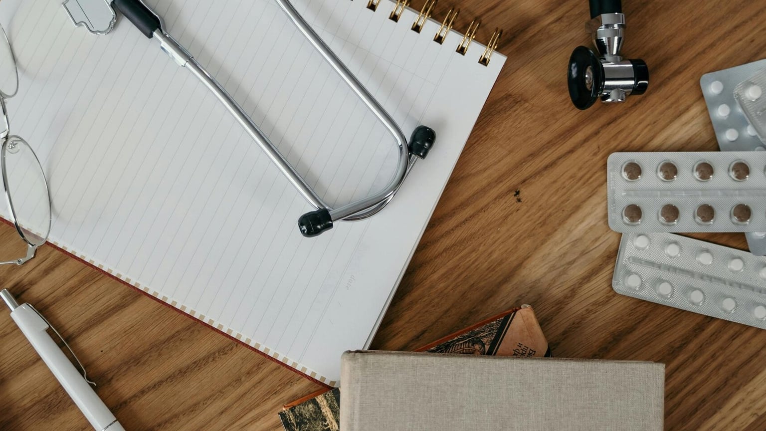 Notebook, stethoscope, glasses, and medication organizers prepared for a health coverage review