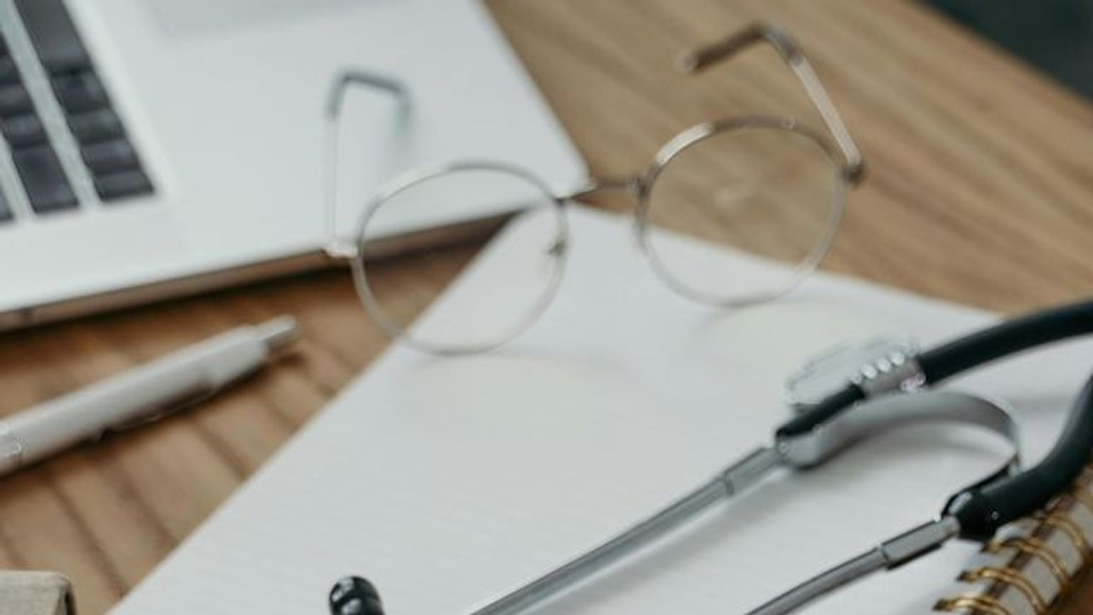 Glasses, a pen, notebook, and stethoscope arranged for a careful coverage review