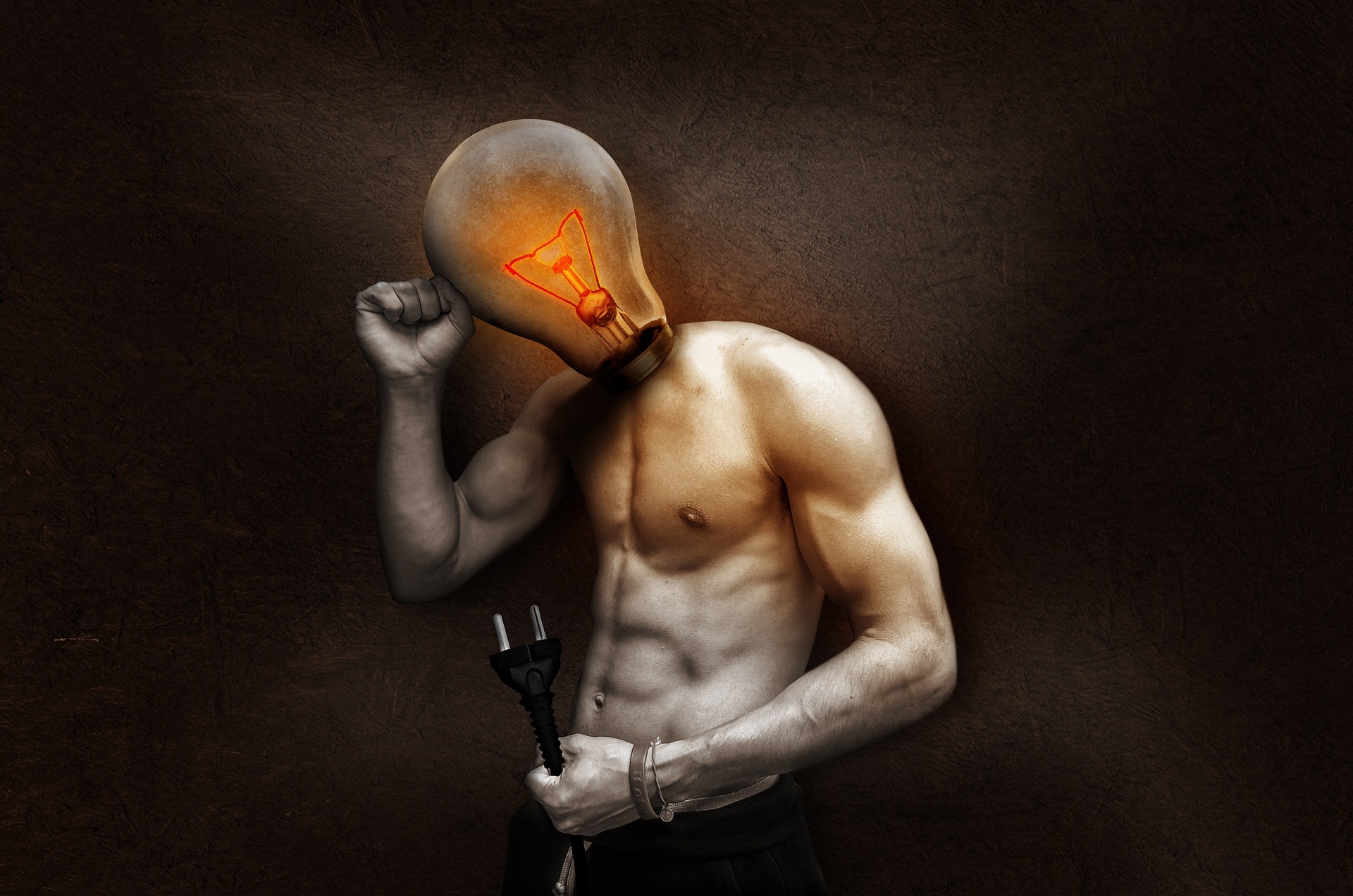 A glowing light bulb held in the dark