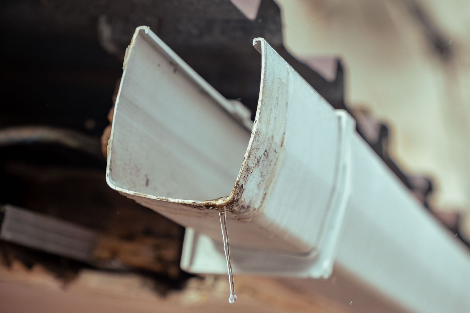 Rainwater dripping from a house gutter during wet weather