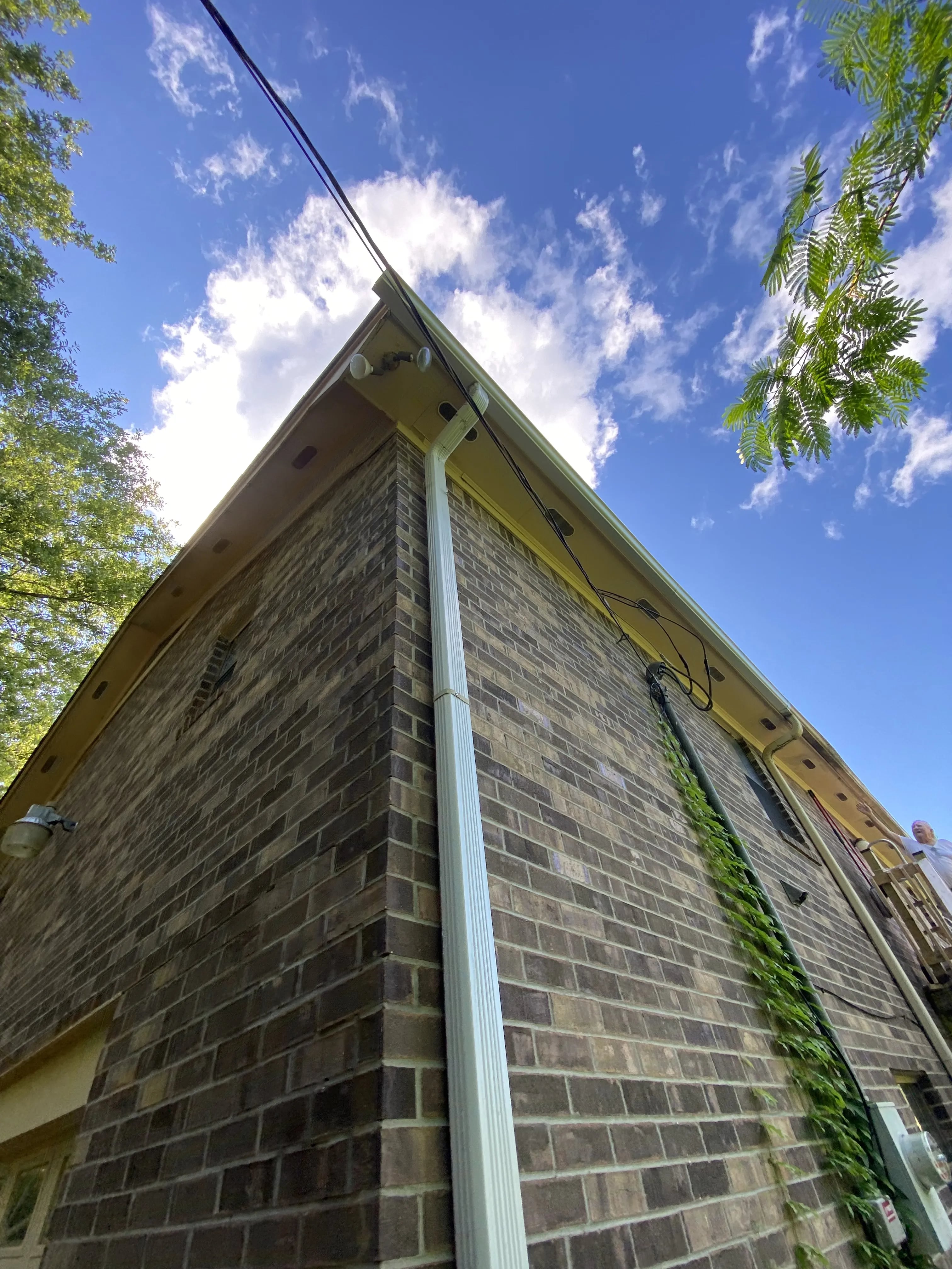 White downspout connected to a gutter on a brick home
