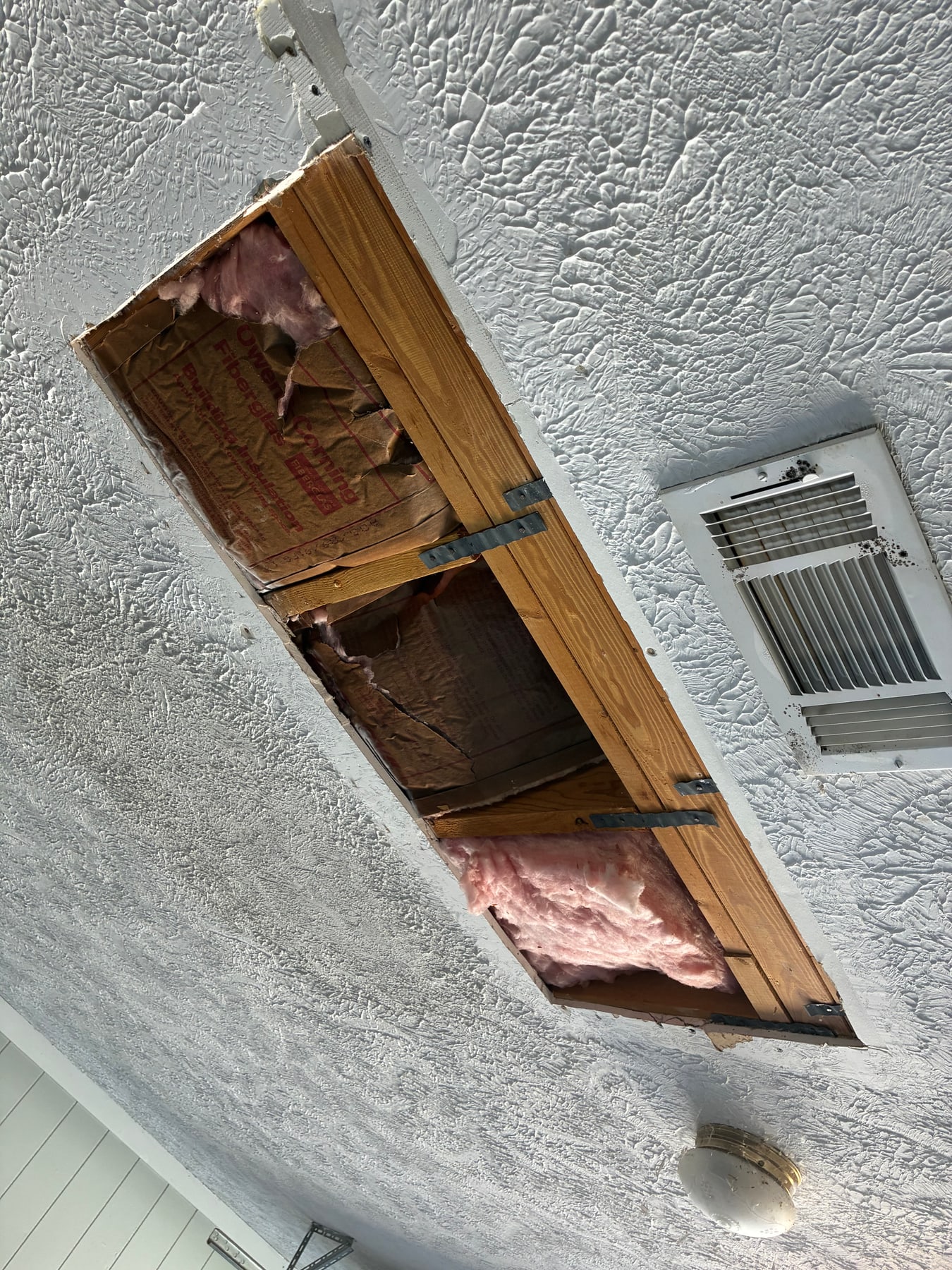 Damaged garage ceiling with an open patch area before repair in Tupelo