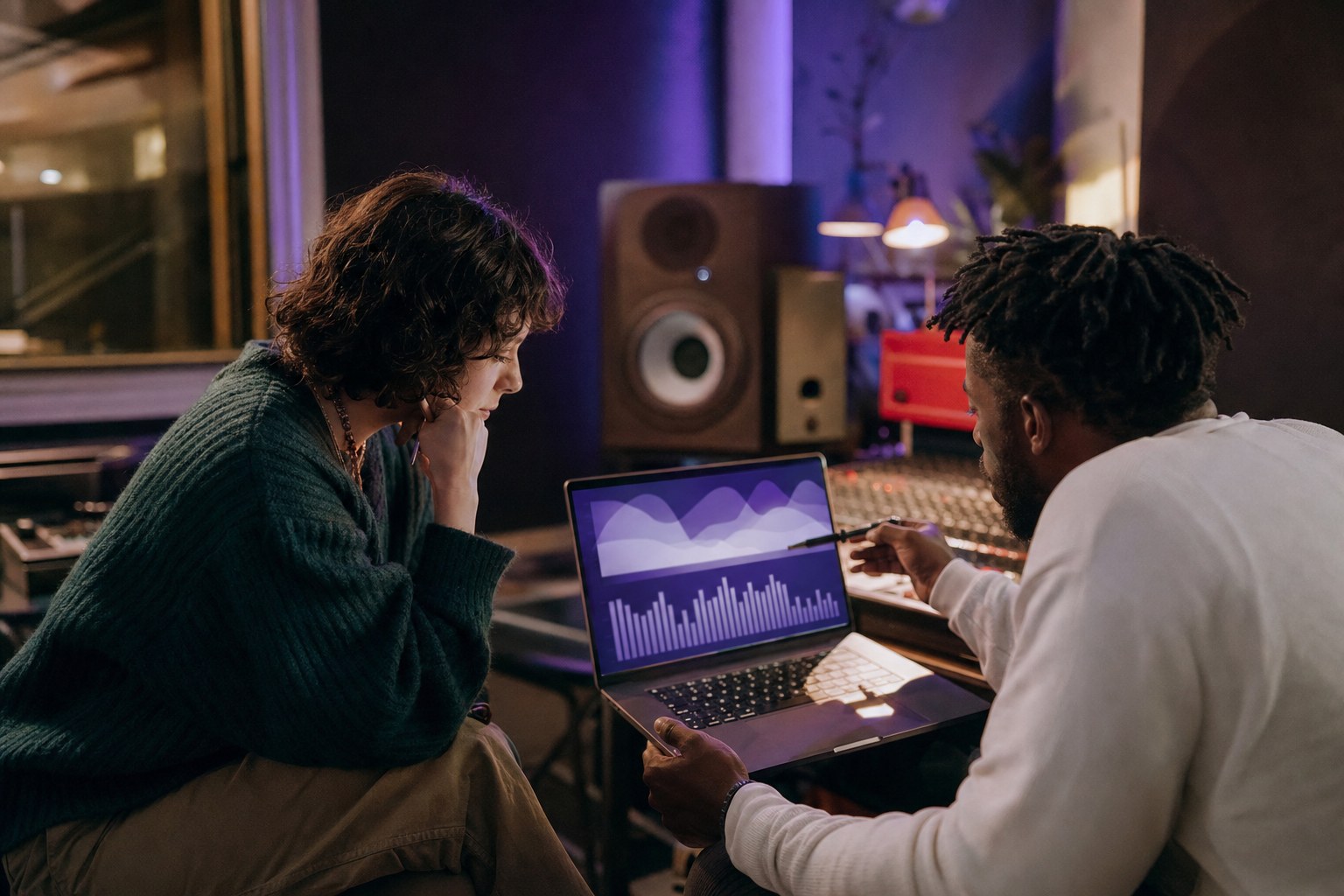 Artist and manager reviewing a video campaign on a laptop in a recording studio