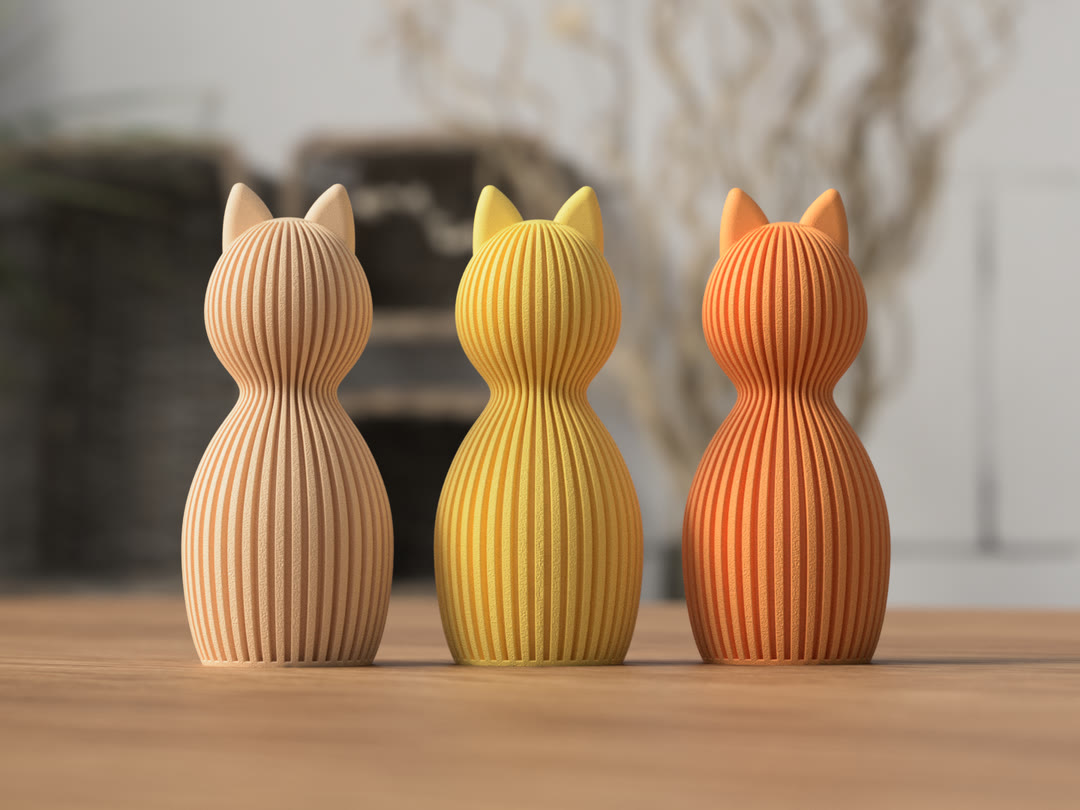 Three ribbed cat-shaped sculptural vases in warm colors