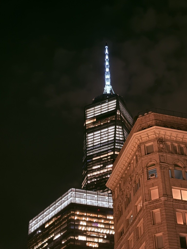 Illuminated tower behind a brick building