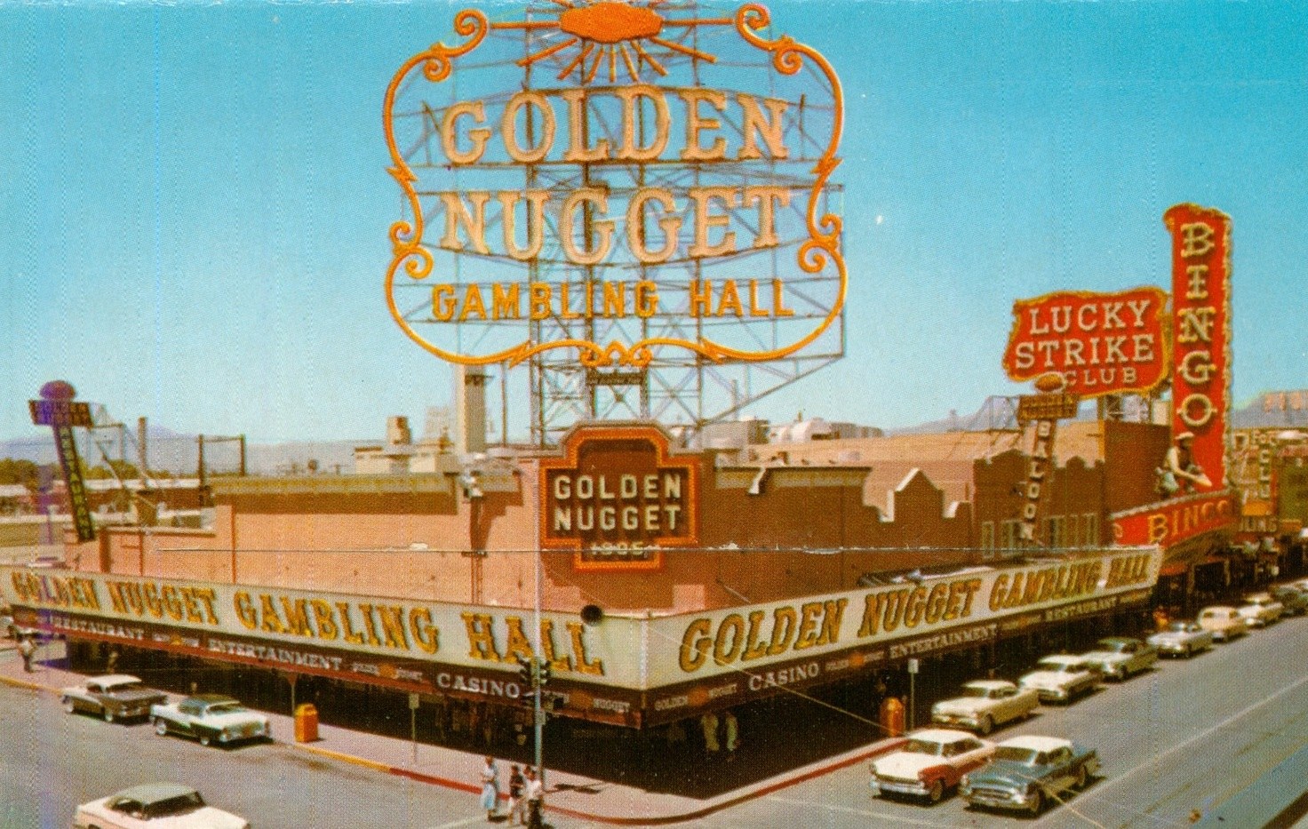 View of the Golden Nugget Gambling Hall building with vintage signage, including the Lucky Strike Club and Bingo, alongside parked cars on the street.