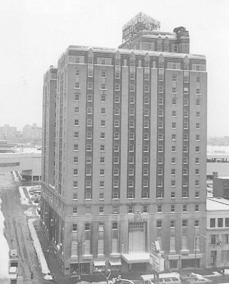 Historic tall brick building with an ornate entrance, captured in a snow-covered urban setting.
