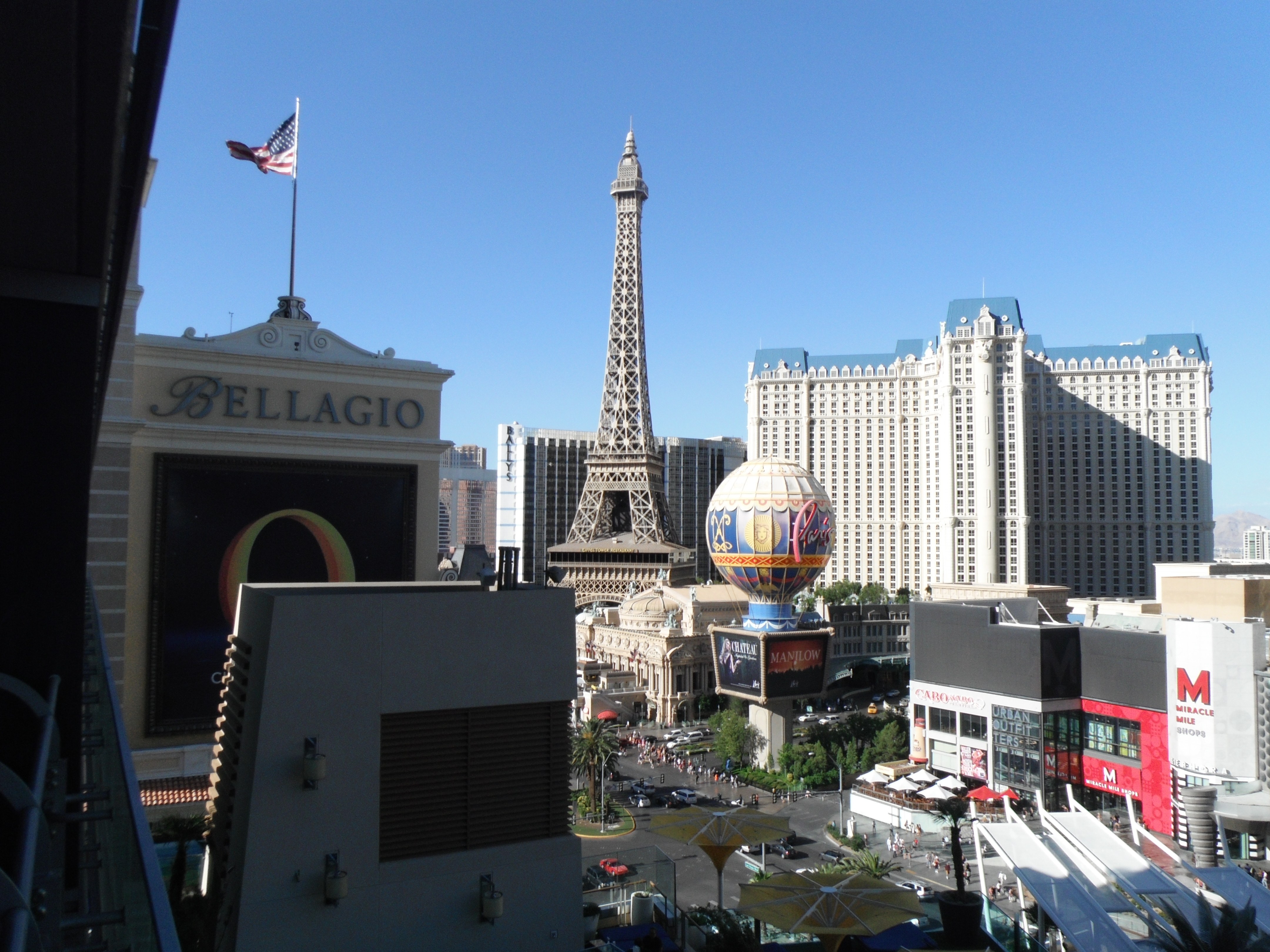 View of the Las Vegas Strip featuring the Bellagio Hotel, the Eiffel Tower replica, and the High Roller observation wheel on a clear day.