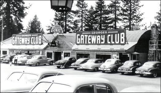 Black and white photo of the Gateway Club and George's Gateway Club with classic cars parked outside, surrounded by trees.