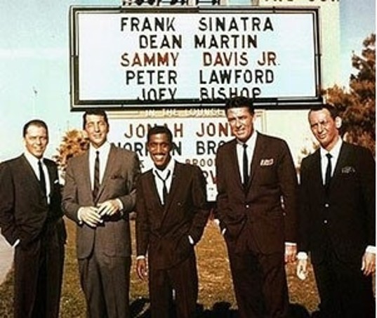 The Rat Pack posing beneath the Sands marquee listing Frank Sinatra, Dean Martin, Sammy Davis Jr., Peter Lawford, and Joey Bishop
