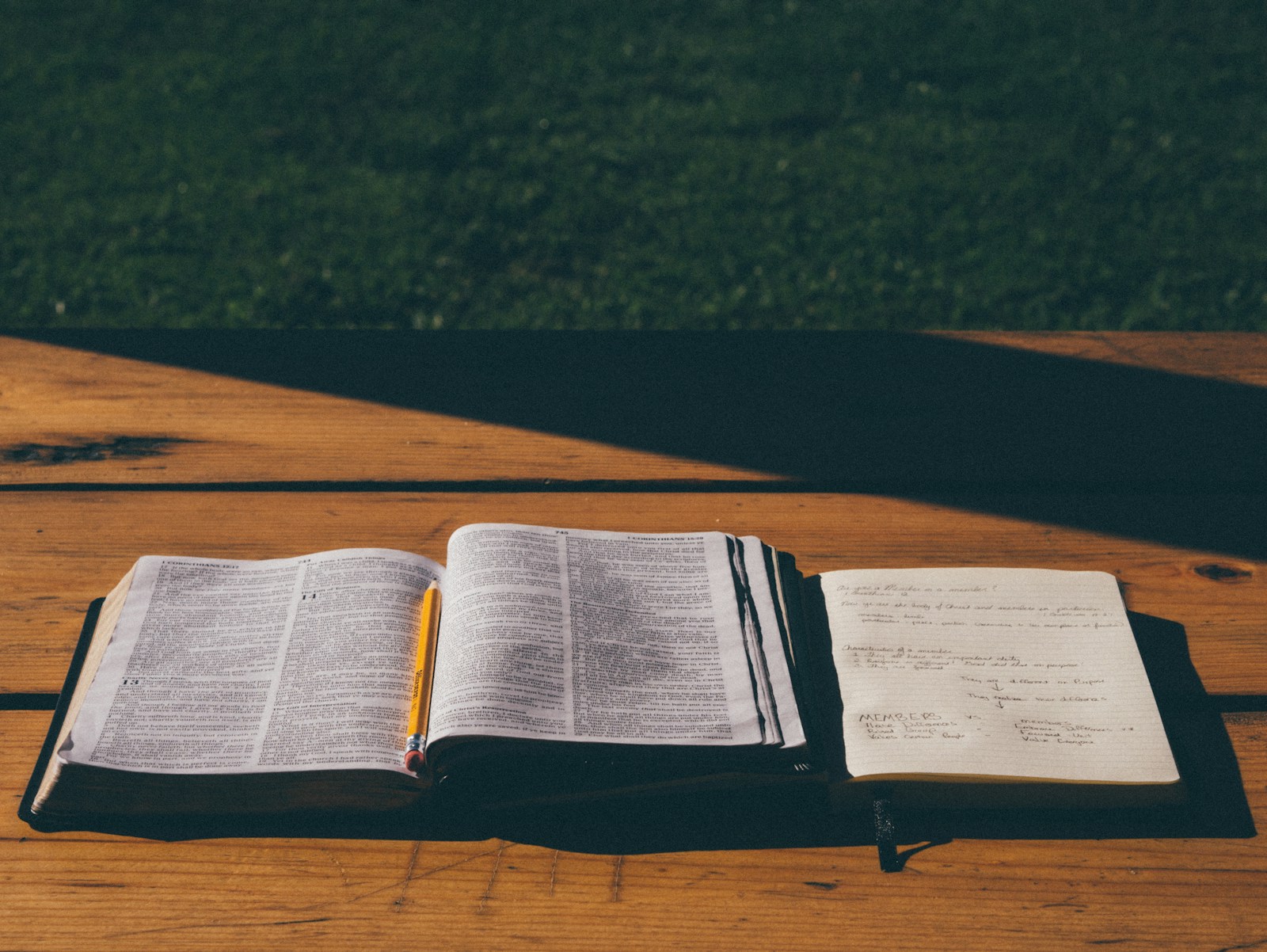 Open Bible, pencil, and study notebook on a wooden table