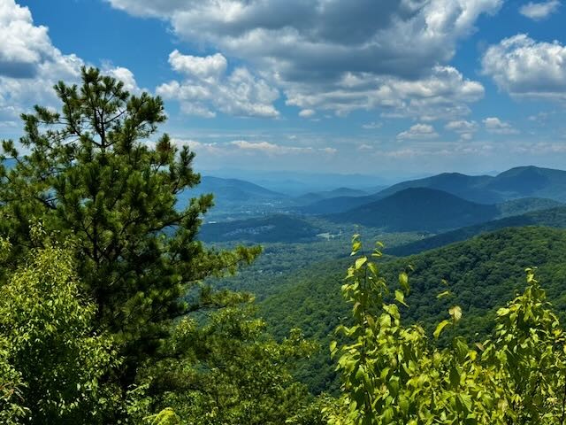 Forested mountain ridges stretching toward the horizon beneath a blue sky