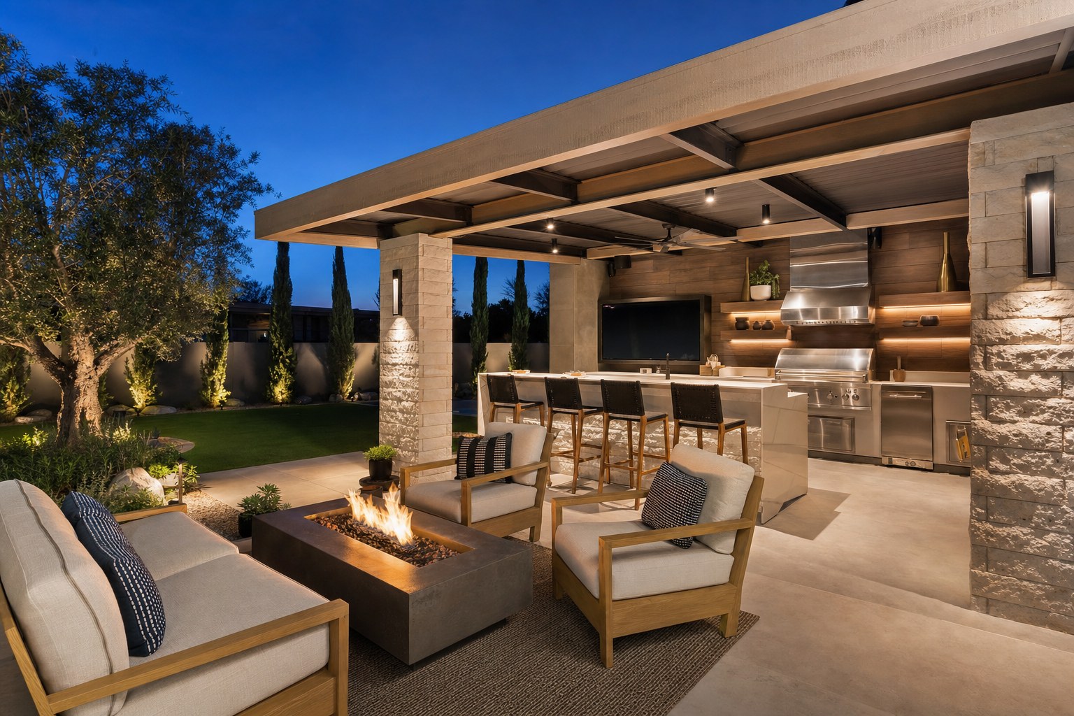 Covered backyard entertaining space with an outdoor kitchen, fire table, bar seating, and lounge chairs