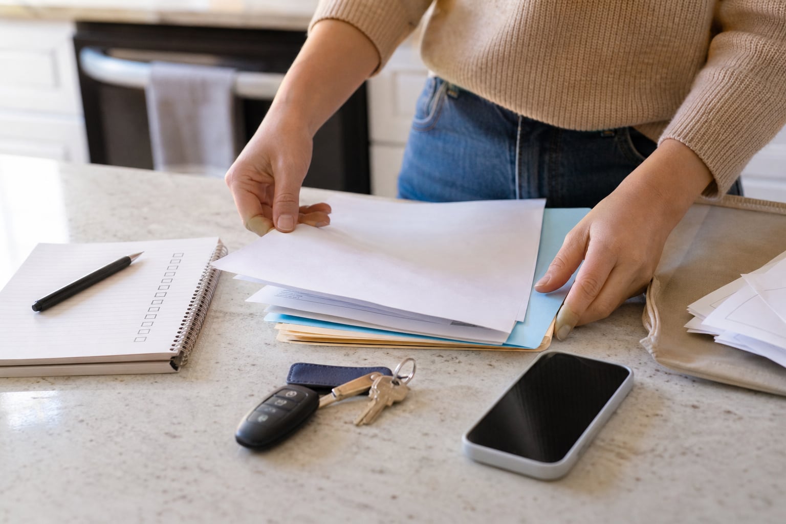 Renter organizing apartment documents, keys, phone, and a checklist before applying