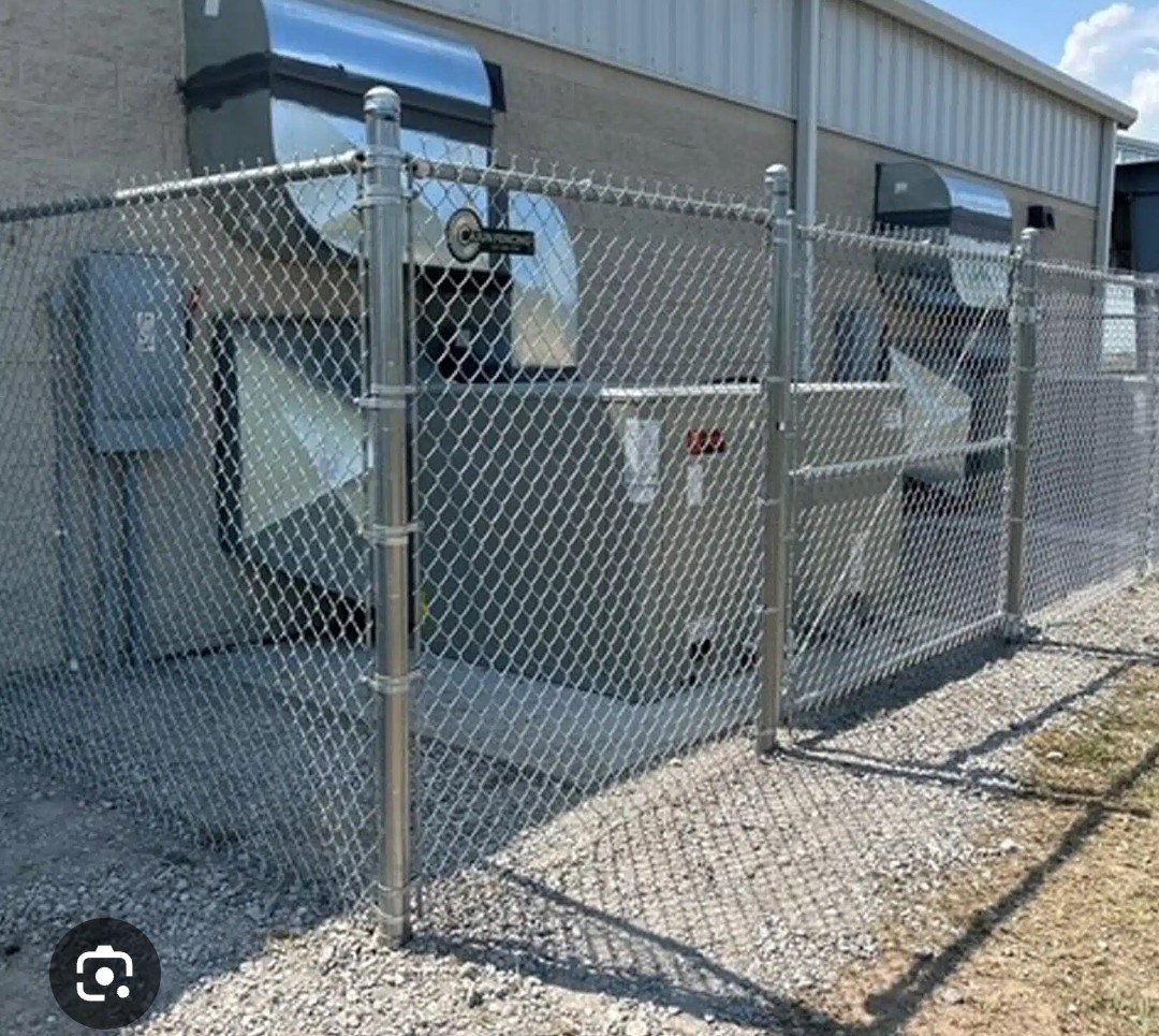Chain-link enclosure protecting equipment beside a business