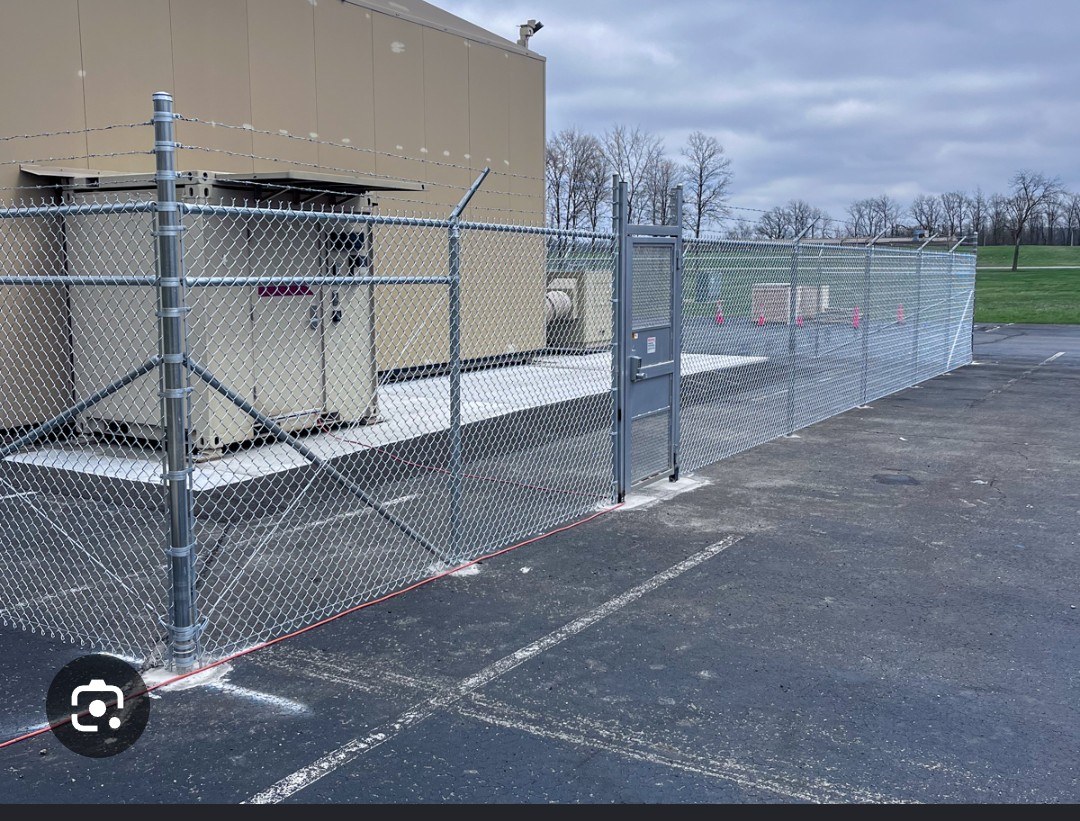 Commercial equipment enclosure with chain-link fencing and a walk gate