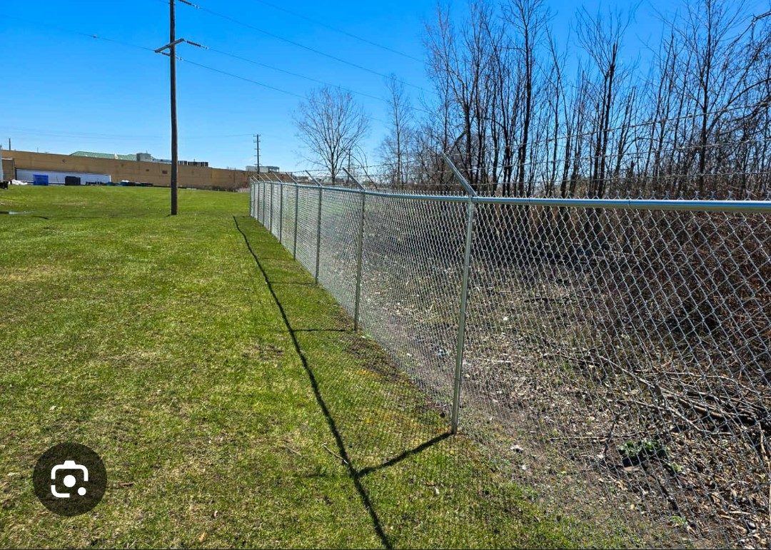 Long commercial chain-link security fence with barbed wire along a property boundary
