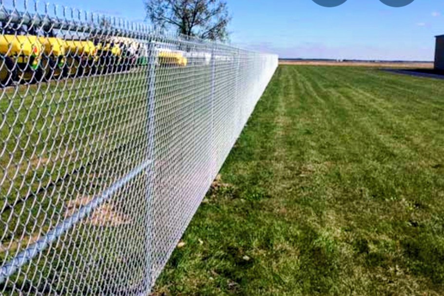 Long run of galvanized chain-link fencing beside a lawn