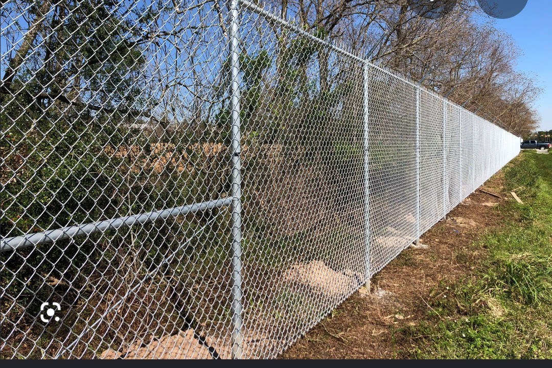 Long galvanized chain-link fence along a roadside