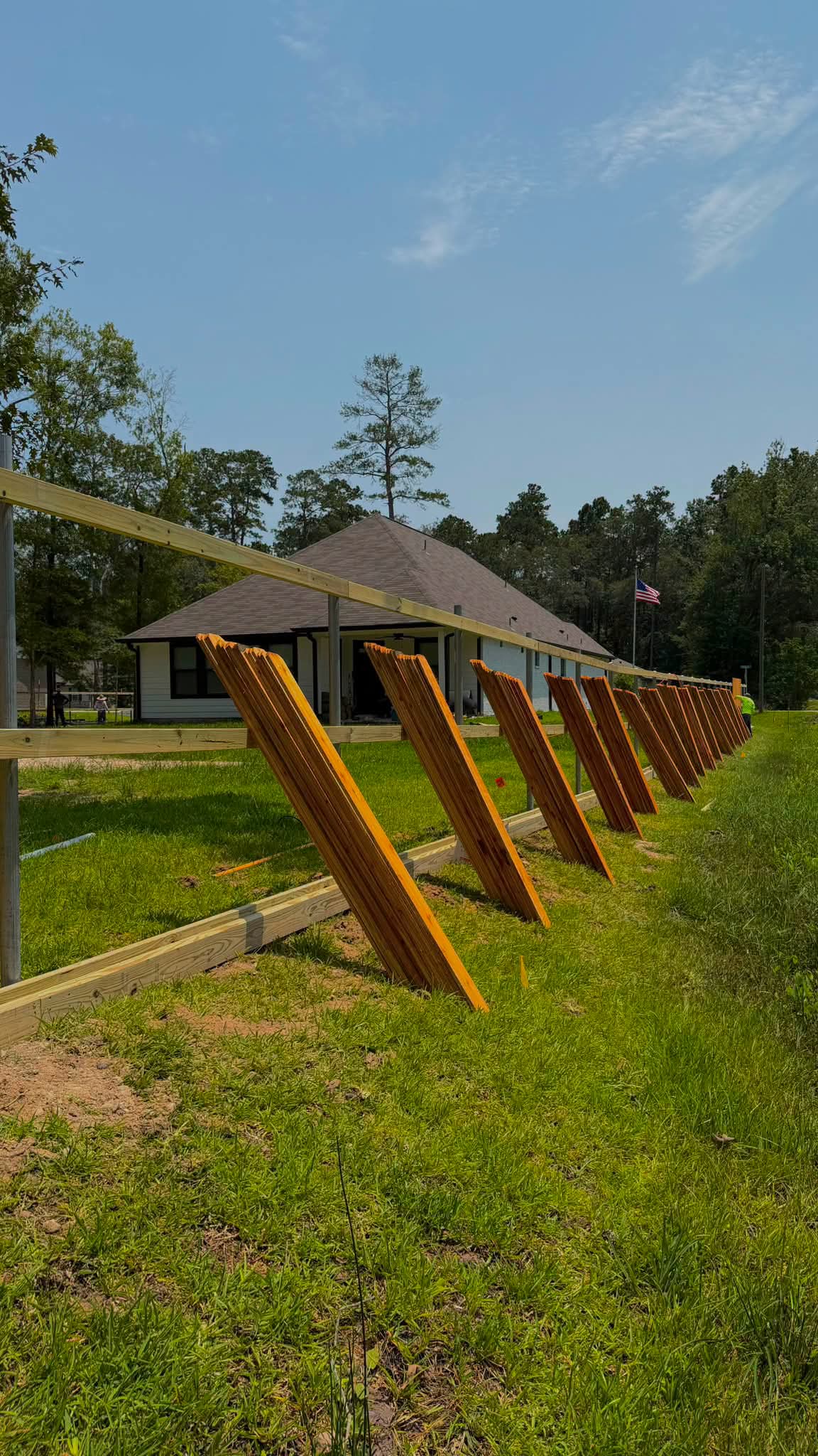 Wood fence pickets staged beside rails during installation