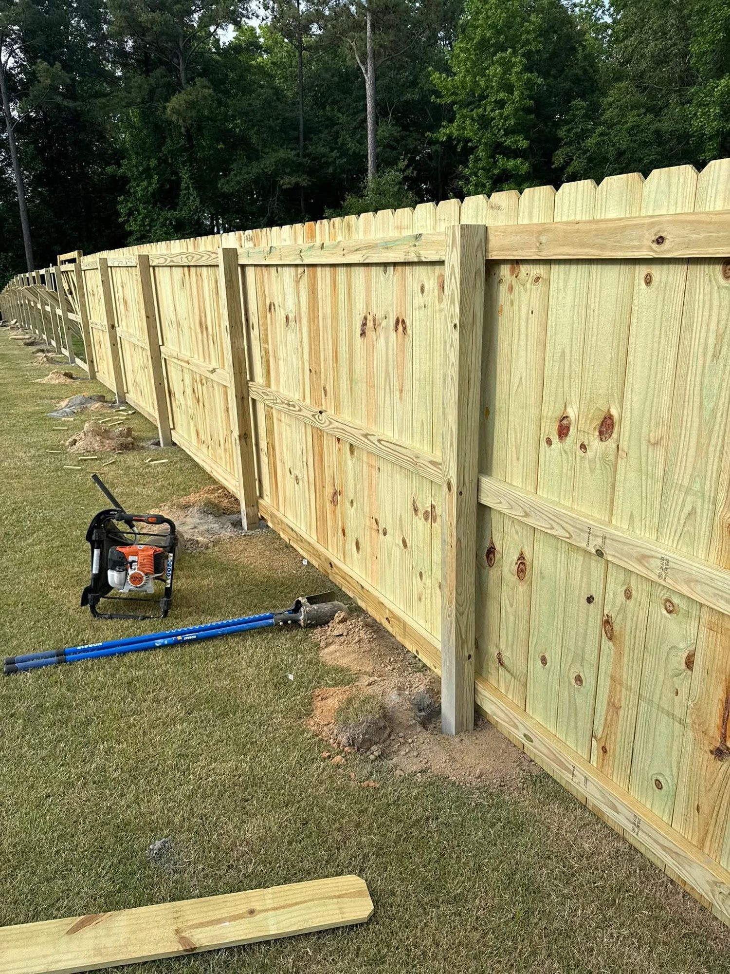 Wood privacy fencing with exposed rails and posts during installation