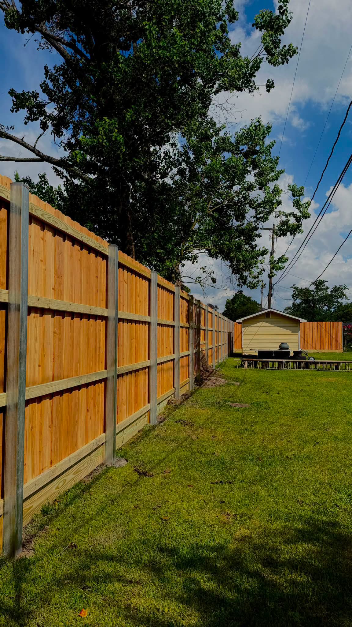 Finished wood privacy fence with steel posts along a backyard