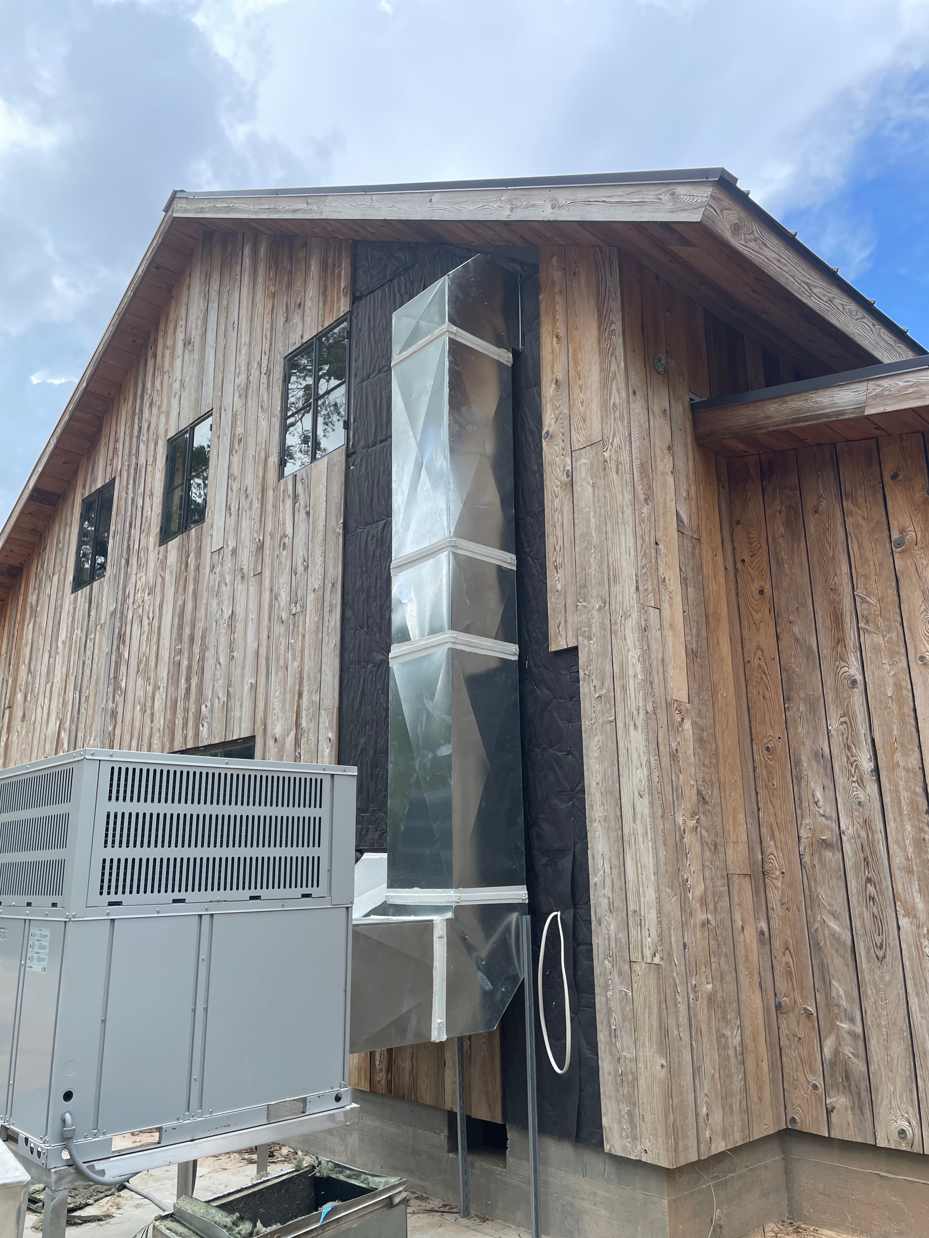 Outdoor HVAC system and vertical ductwork beside a building