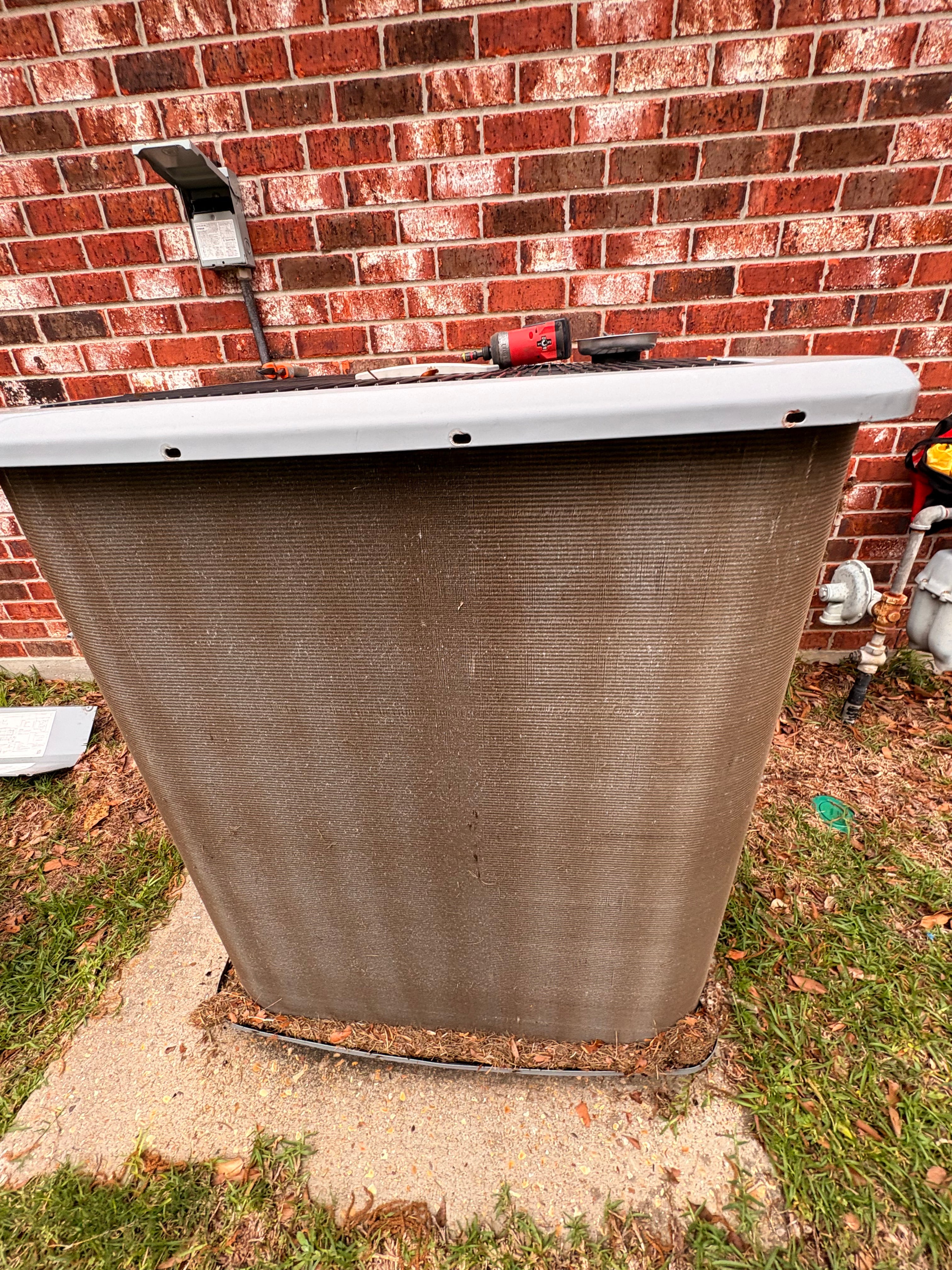 Outdoor air conditioning condenser installed beside a brick home