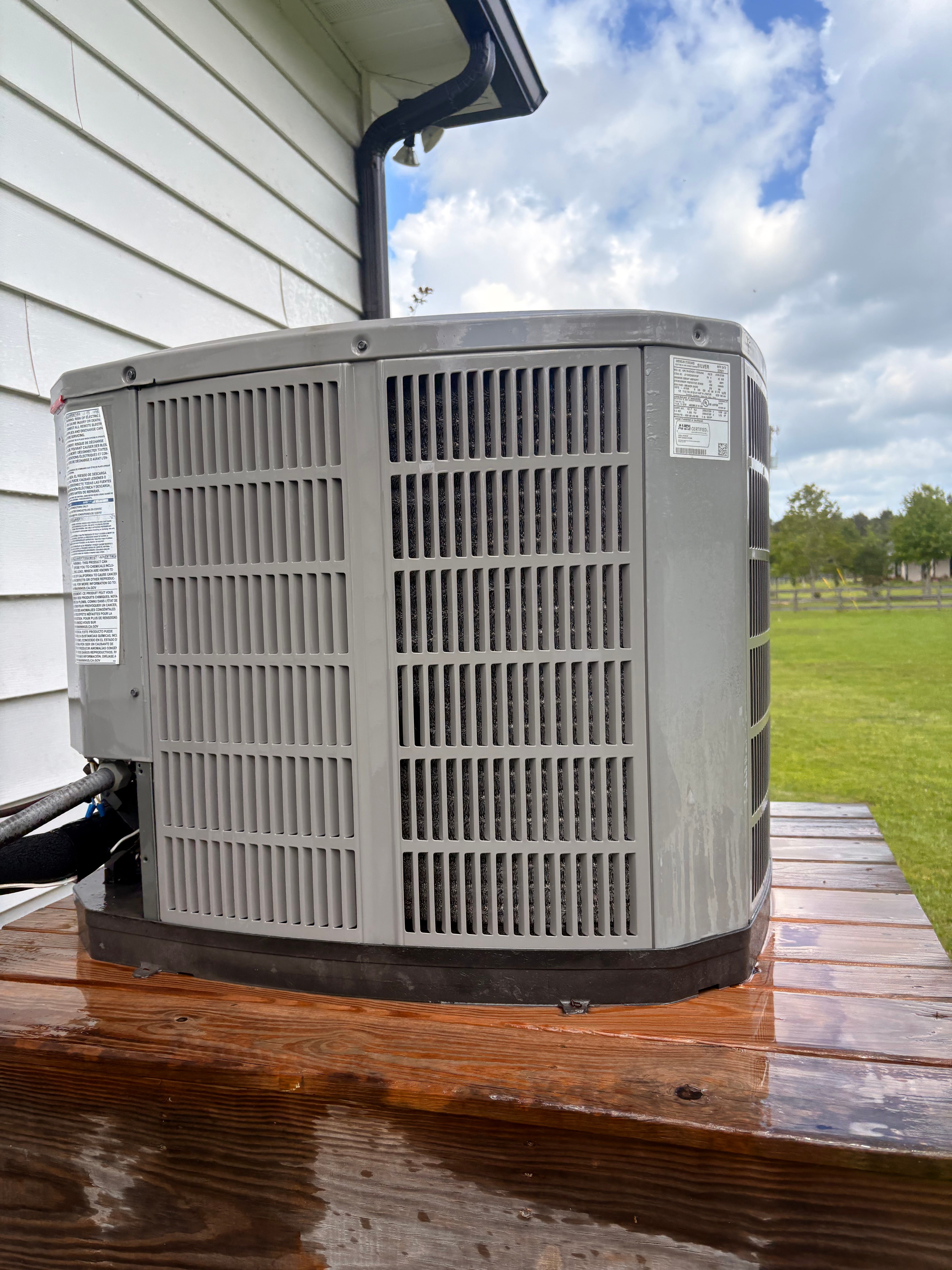 New residential outdoor air conditioning unit on a raised platform