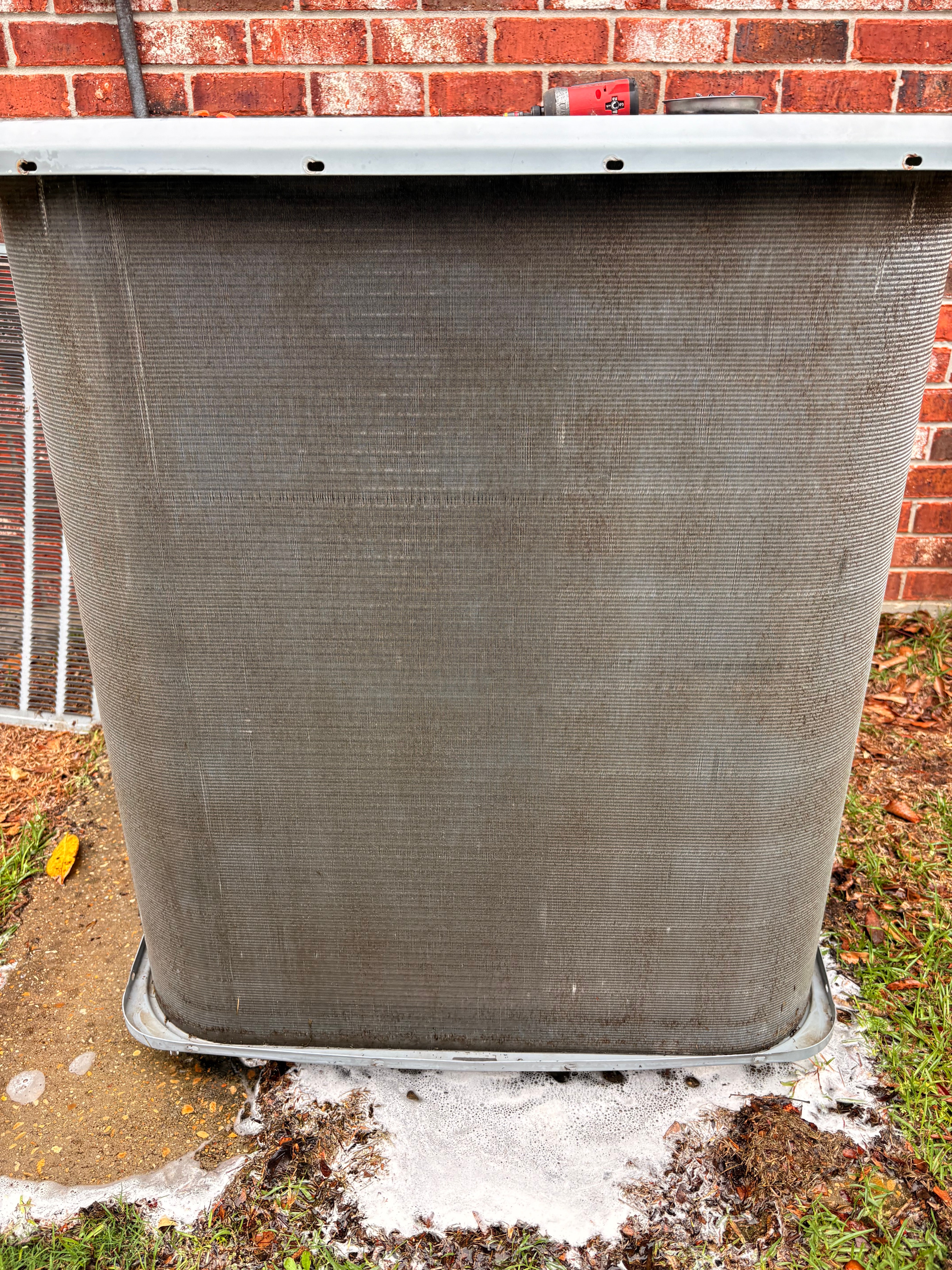 Outdoor air conditioning condenser beside a brick home