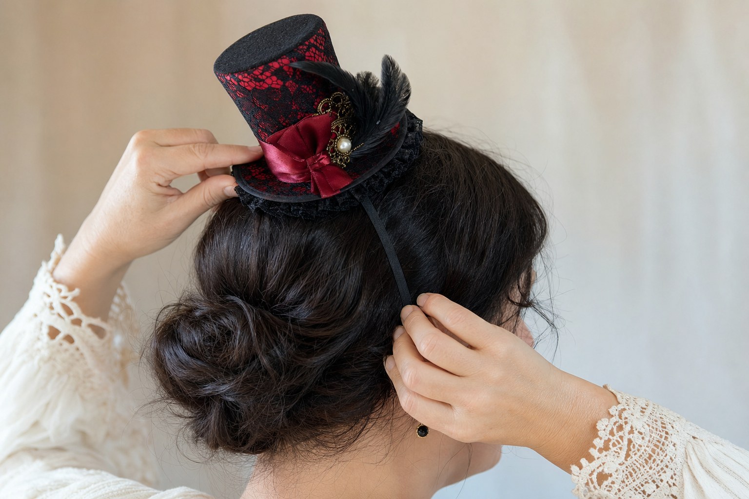 Hands positioning a small black and red circus-style mini top hat on a headband