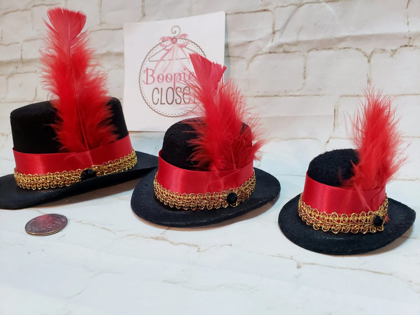 Black ringmaster mini top hat with red ribbon, gold trim, and red feathers