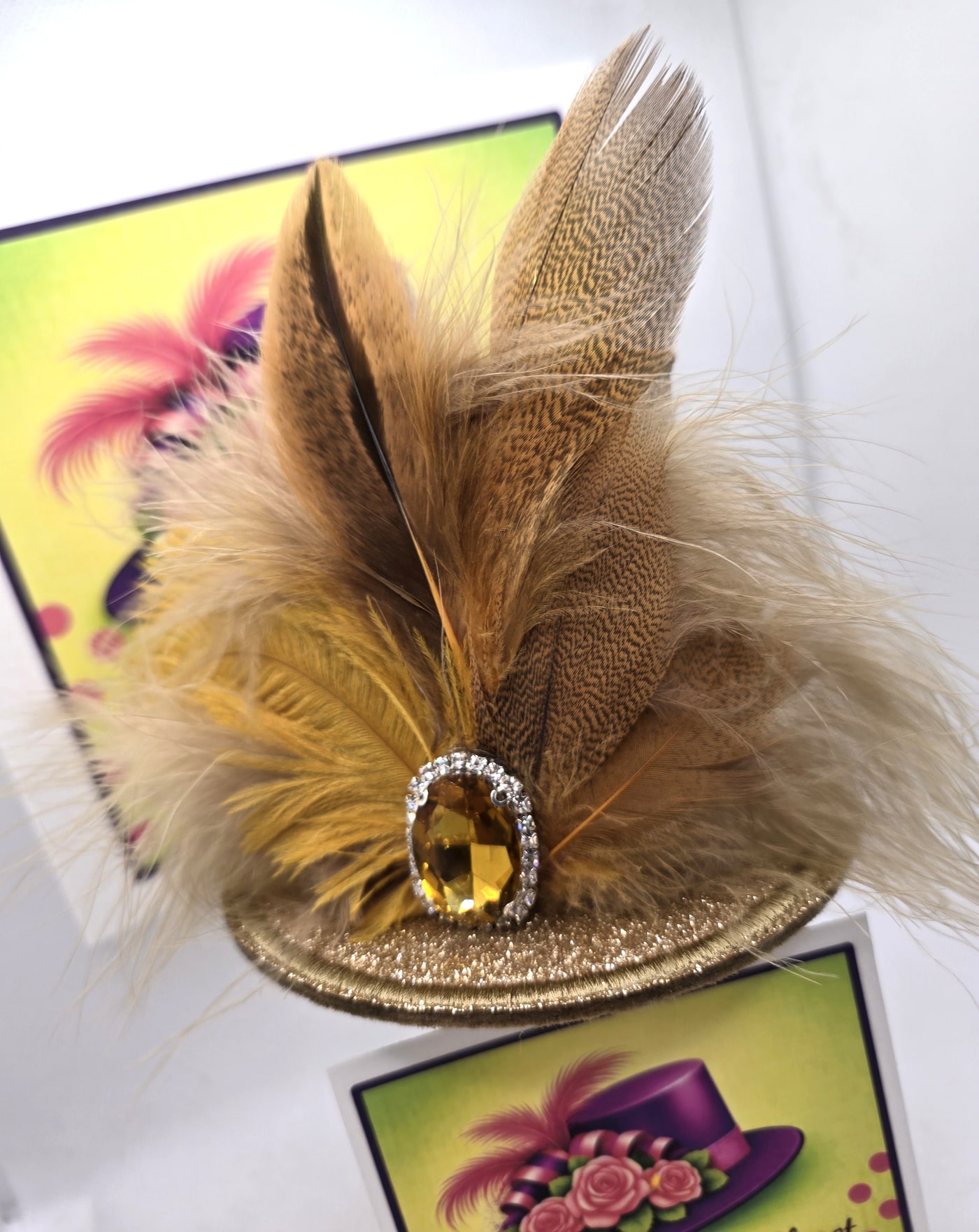 Gold mini top hat with layered feathers and a jeweled accent