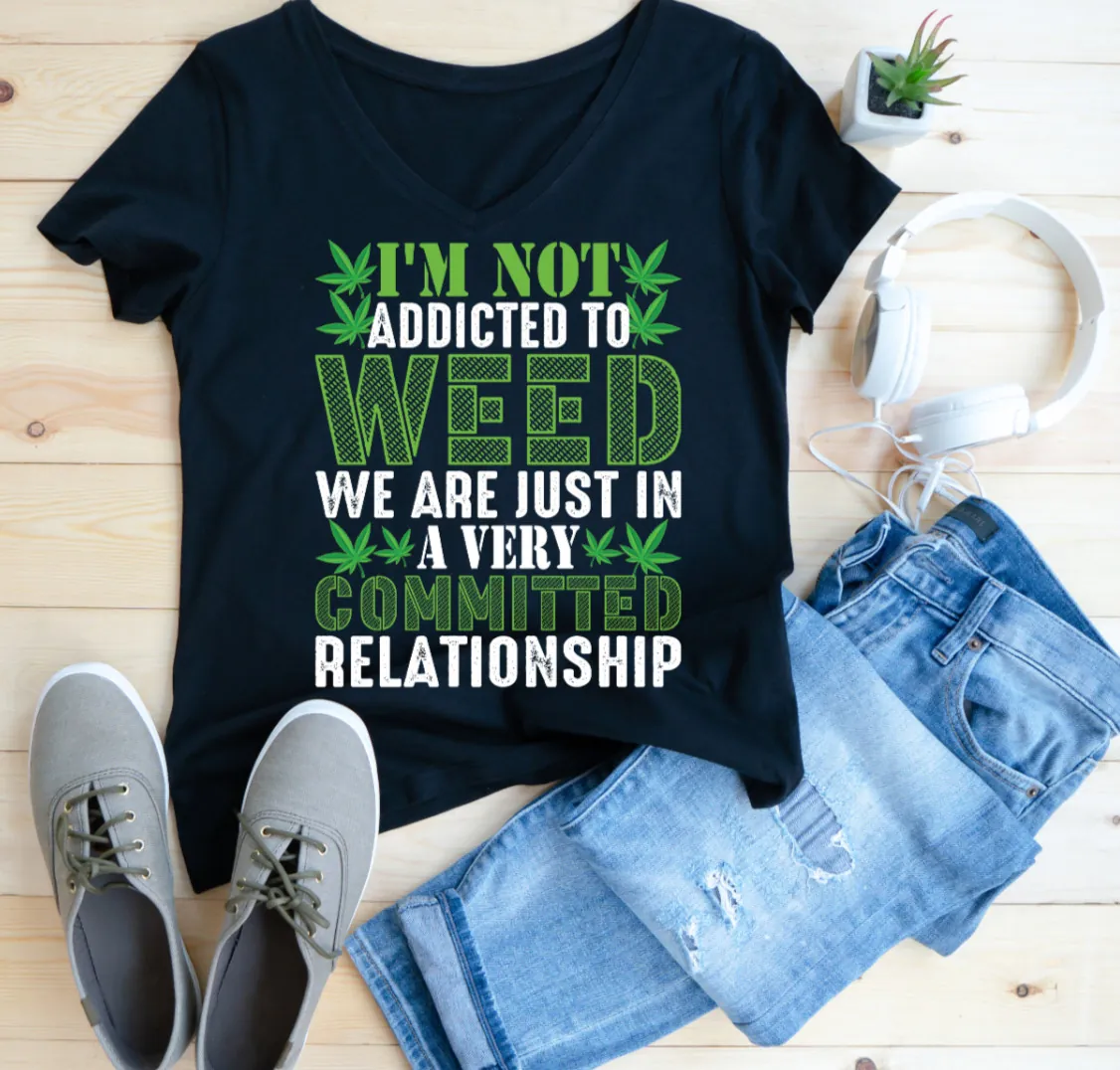 Black tee shirt with funny weed quote and denim jeans on white background.