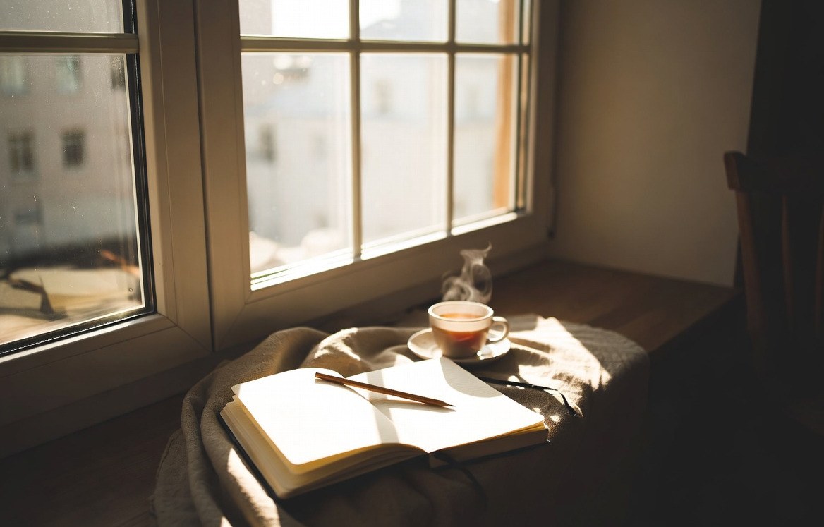 A cup of tea and an open notebook in warm morning light
