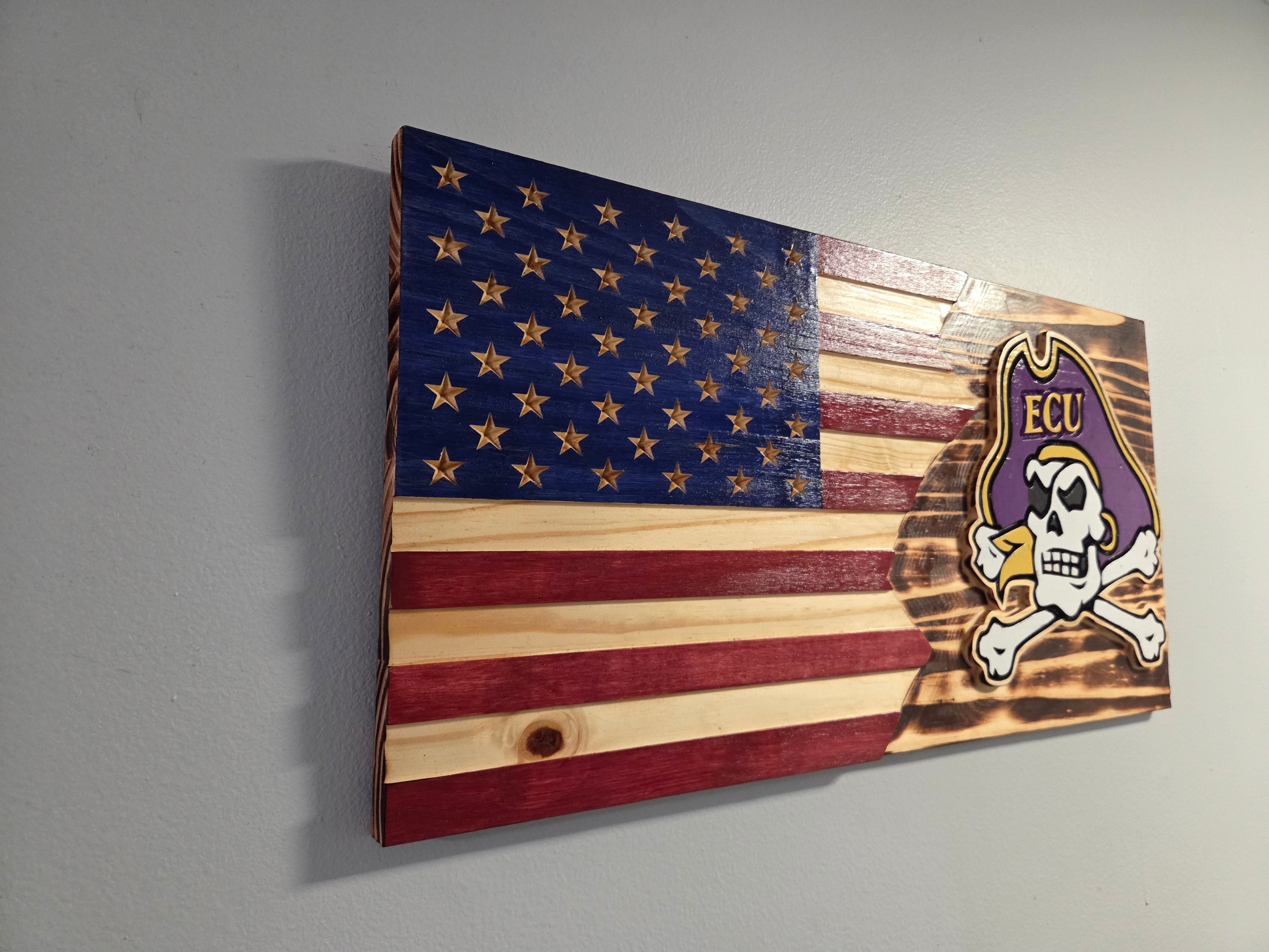 Close view of a carved ECU Pirates wooden flag with layered purple and gold details