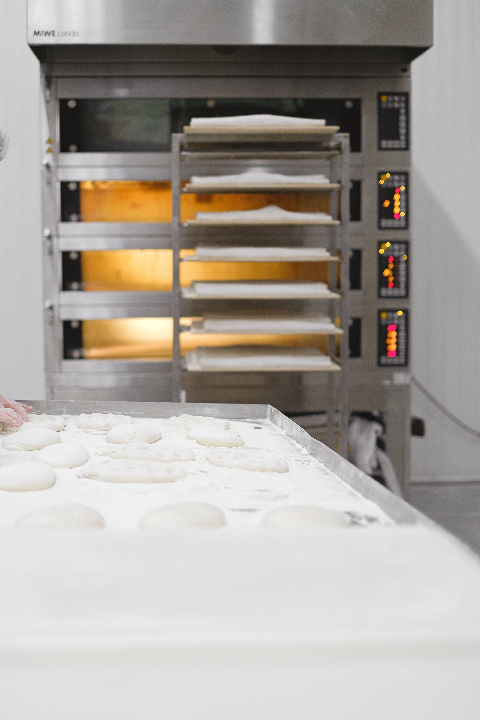 Dough preparation beside racks and ovens in a commercial bakery