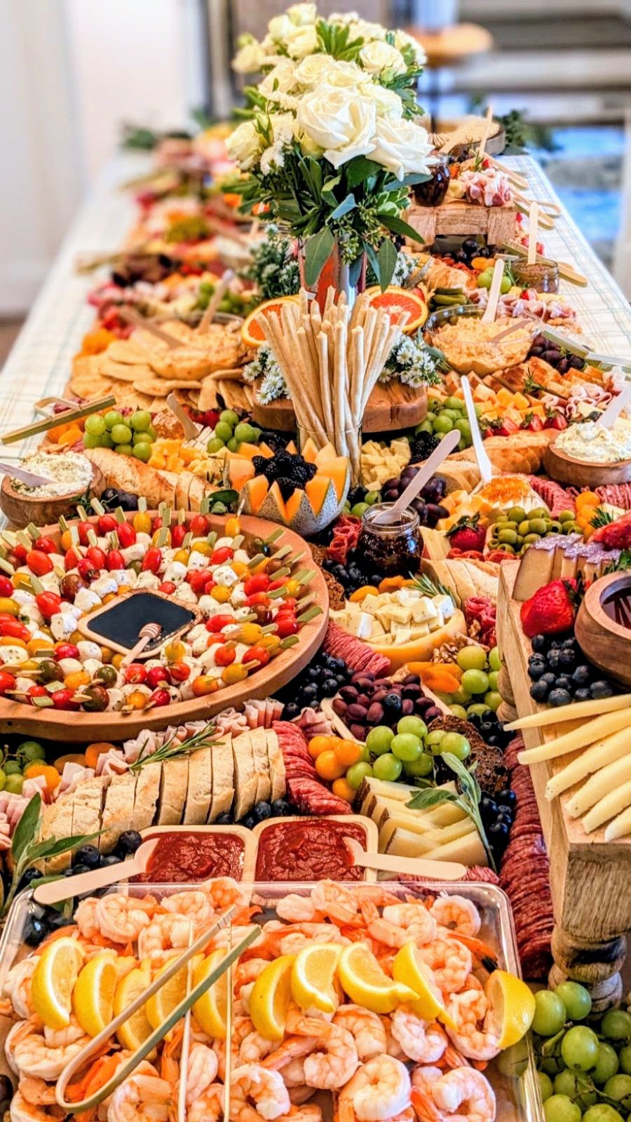 A full Yellow House Grazing table with flowers, fruit, cheeses and charcuterie