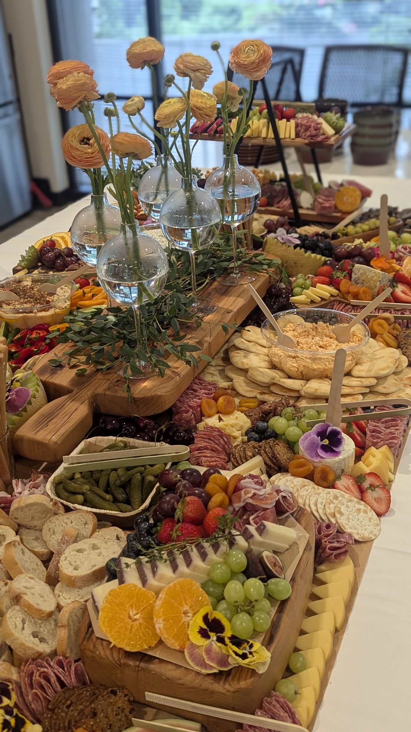 A Yellow House Grazing table arranged with cheeses, crackers, fruit and flowers