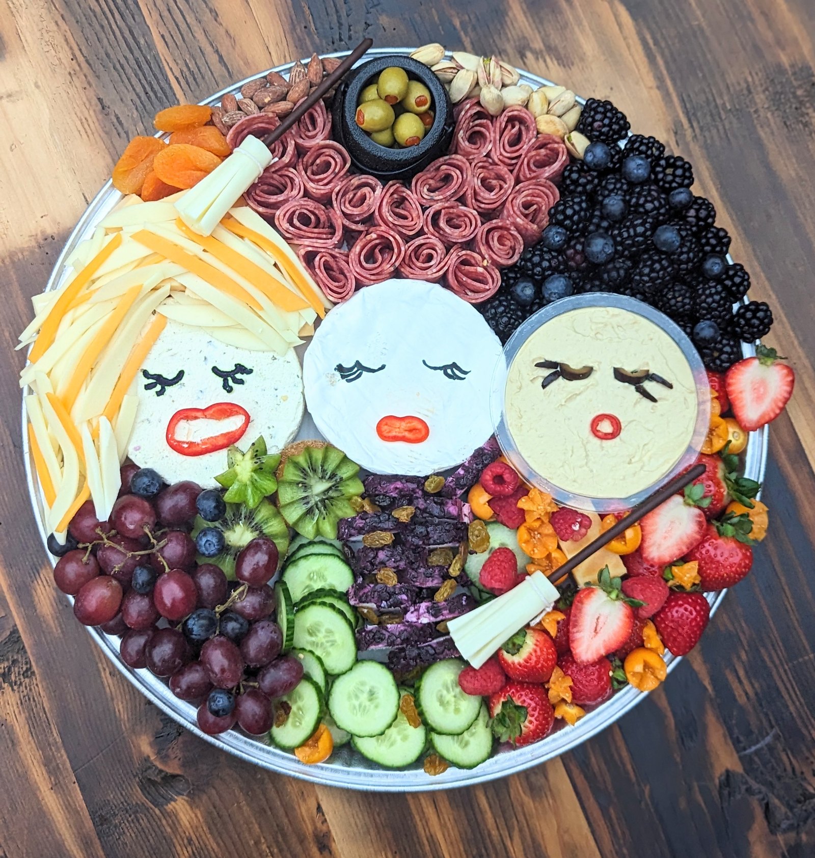 Halloween grazing board with three cheese faces, salami roses and fresh fruit